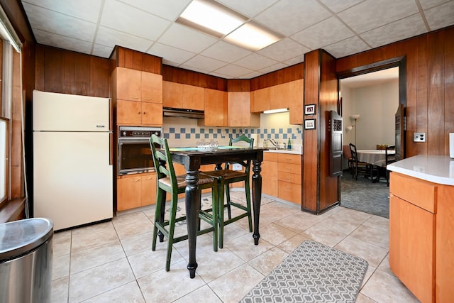 366 Kansas St, Winona, MN 55987 - kitchen with freestanding refrigerator, stainless steel oven, backsplash, under cabinet range hood, and light countertops