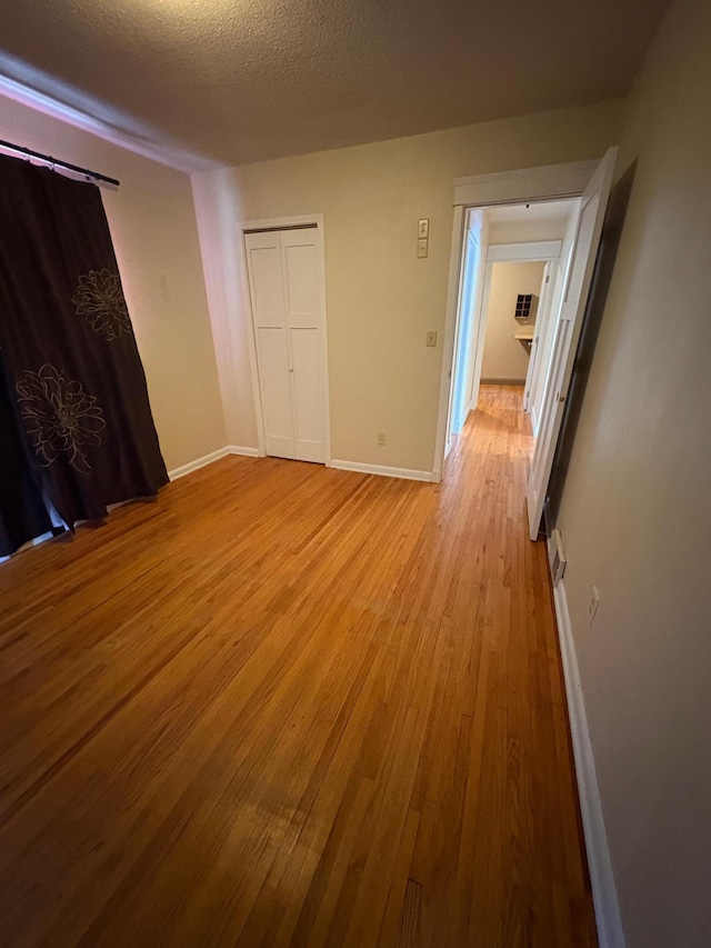 207 Meadow Ln, Benson, MN 56215 - unfurnished bedroom with light wood finished floors, a textured ceiling, and a closet