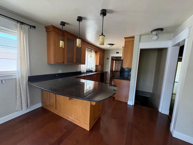 207 Meadow Ln, Benson, MN 56215 - kitchen featuring a peninsula, dark wood-style floors, pendant lighting, brown cabinets, and a breakfast bar