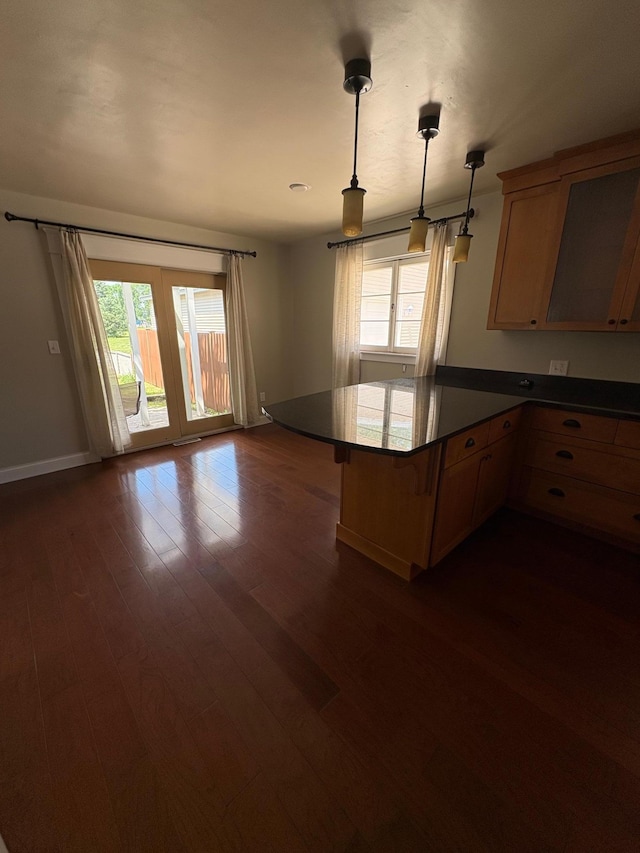 207 Meadow Ln, Benson, MN 56215 - kitchen featuring dark wood-style flooring, a peninsula, dark countertops, decorative light fixtures, and a breakfast bar area
