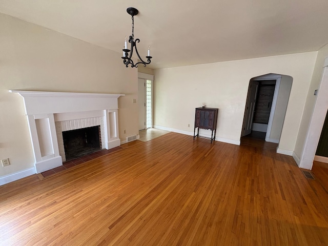 207 Meadow Ln, Benson, MN 56215 - unfurnished living room featuring a fireplace, light wood-style floors, arched walkways, and a chandelier