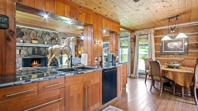 W13263 Hutchinson Rd, Big Bend Twp, WI 54819 - kitchen featuring dishwasher, brown cabinetry, wood walls, wood finished floors, and a fireplace
