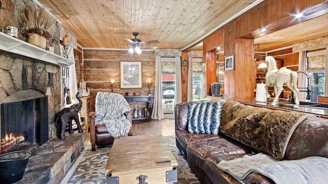 W13263 Hutchinson Rd, Big Bend Twp, WI 54819 - living room featuring a stone fireplace, wood walls, wooden ceiling, wood finished floors, and a ceiling fan