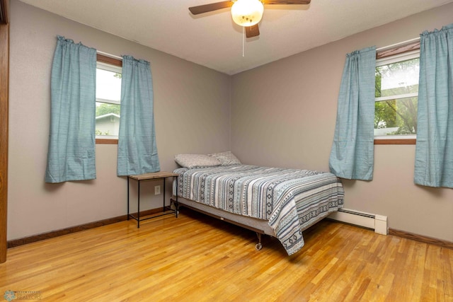 402 5th St NE, Barnesville, MN 56514 - bedroom featuring multiple windows, wood finished floors, ceiling fan, and a baseboard heating unit