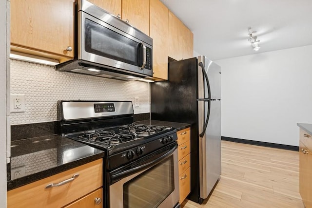 2800 44th St Unit 401, Minneapolis, MN 55410 - kitchen with stainless steel appliances, tasteful backsplash, light wood finished floors, and dark stone counters