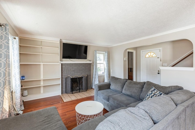 1290 Matilda St, Saint Paul, MN 55117 - living room featuring arched walkways, wood finished floors, a brick fireplace, crown molding, and stairway