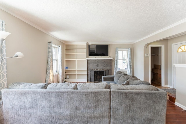 1290 Matilda St, Saint Paul, MN 55117 - living room featuring dark wood finished floors, a textured ceiling, a fireplace, ornamental molding, and arched walkways