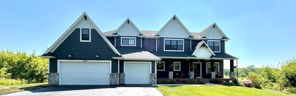 8750 Vernon St, Greenfield, MN 55373 - craftsman inspired home with covered porch, asphalt driveway, board and batten siding, a front lawn, and a garage