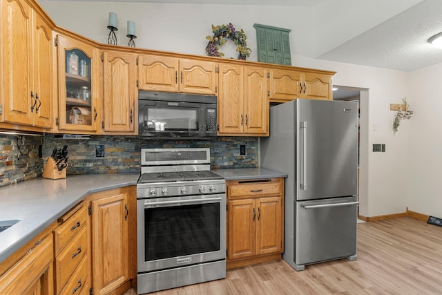 4508 192nd St, Fair Haven Twp, MN 55382 - kitchen featuring appliances with stainless steel finishes, light wood finished floors, tasteful backsplash, glass insert cabinets, and light countertops