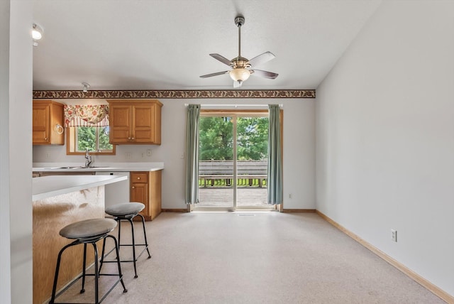 6617 378th St, North Branch, MN 55056 - kitchen with light countertops, a ceiling fan, a kitchen bar, dishwashing machine, and brown cabinetry