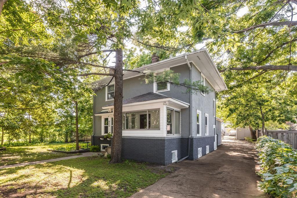 4215 Unity Ave N, Robbinsdale, MN 55422 - view of front of home featuring brick siding, a chimney, stucco siding, and driveway