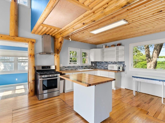 7247 Eden Prairie Rd, Eden Prairie, MN 55346 - kitchen featuring butcher block countertops, stainless steel range with gas cooktop, wall chimney exhaust hood, open shelves, and white cabinetry