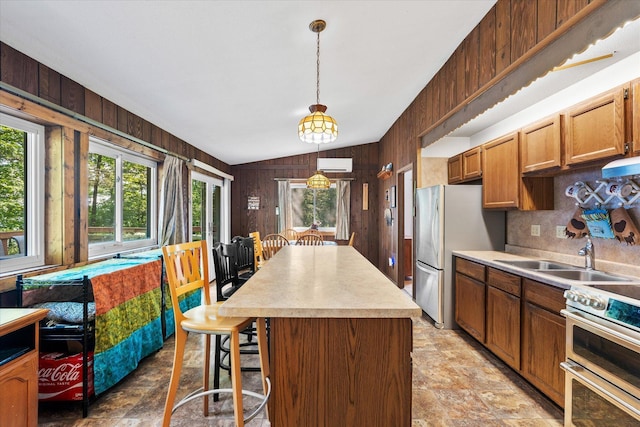 36977 Shoreland Rd, Sturgeon Lake, MN 55783 - kitchen with appliances with stainless steel finishes, wood walls, stone finish flooring, a breakfast bar, and a kitchen island