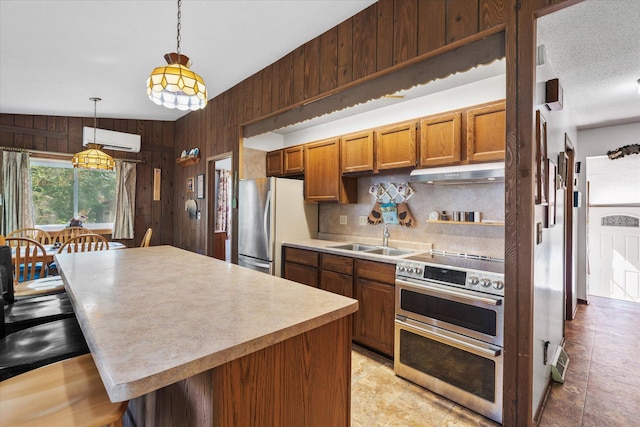 36977 Shoreland Rd, Sturgeon Lake, MN 55783 - kitchen with stainless steel appliances, under cabinet range hood, a wall mounted AC, wooden walls, and tasteful backsplash