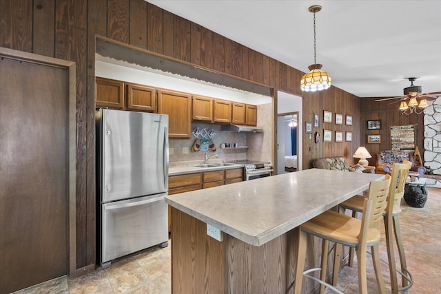 36977 Shoreland Rd, Sturgeon Lake, MN 55783 - kitchen with appliances with stainless steel finishes, wood walls, light countertops, a ceiling fan, and under cabinet range hood
