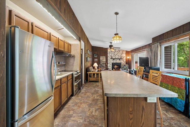 36977 Shoreland Rd, Sturgeon Lake, MN 55783 - kitchen featuring stainless steel appliances, wooden walls, stone finish floors, a fireplace, and a kitchen island