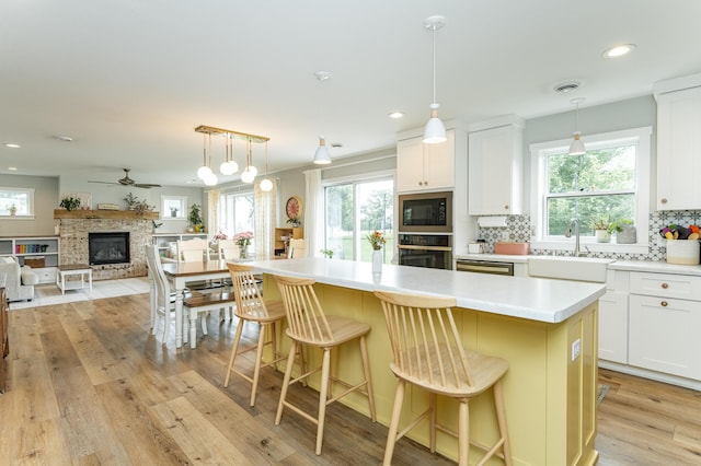 2990 Pinewood Ridge Dr SE, Rochester, MN 55904 - kitchen with backsplash, light wood-style flooring, oven, a ceiling fan, and a kitchen island