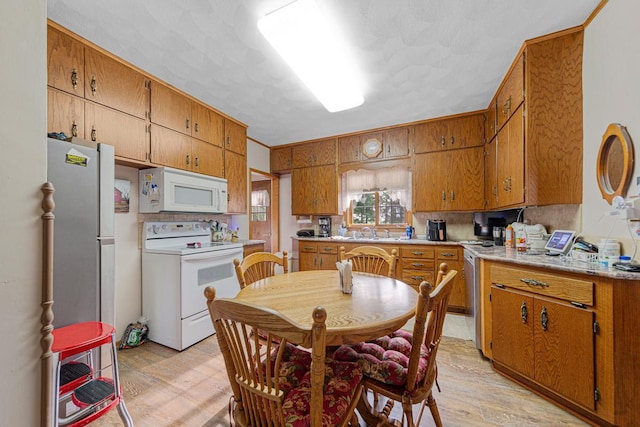 600 168th St, Summit Twp, MN 56026 - kitchen with white appliances, brown cabinetry, light wood-style floors, light countertops, and tasteful backsplash