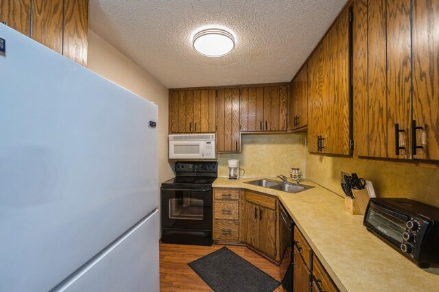 8431 Toledo Ave N, Brooklyn Park, MN 55443 - kitchen with black appliances, a textured ceiling, light countertops, brown cabinets, and wood finished floors