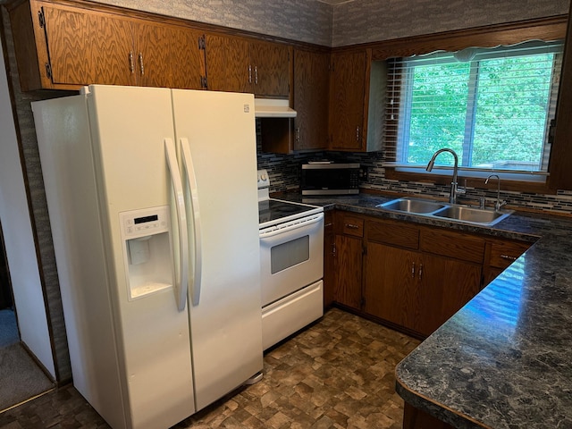 925 Holcombe Ave, Litchfield, MN 55355 - kitchen featuring white appliances, under cabinet range hood, dark countertops, tasteful backsplash, and brown cabinetry