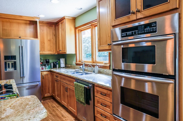 12310 Grouse St NW, Coon Rapids, MN 55448 - kitchen with appliances with stainless steel finishes, light wood-style flooring, light stone counters, brown cabinetry, and recessed lighting