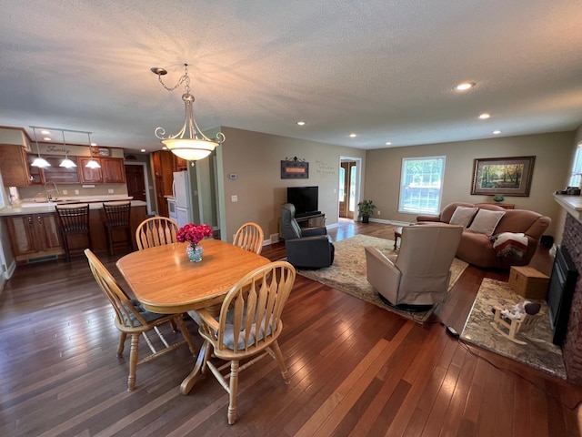 1010 Oakwood Ave, Benson, MN 56215 - dining area featuring dark wood-style floors, a fireplace, recessed lighting, and a textured ceiling