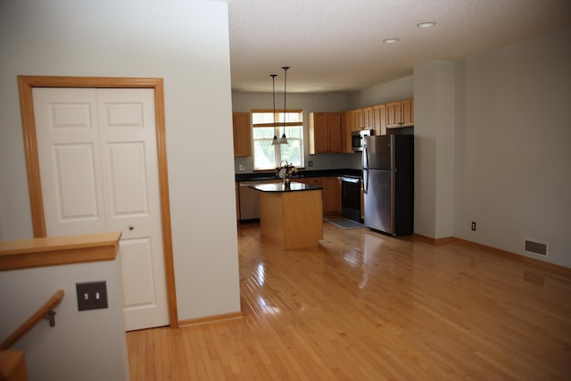 2690 Pinkspire Ln E, Maplewood, MN 55119 - kitchen featuring appliances with stainless steel finishes, a kitchen island, light wood finished floors, dark countertops, and hanging light fixtures