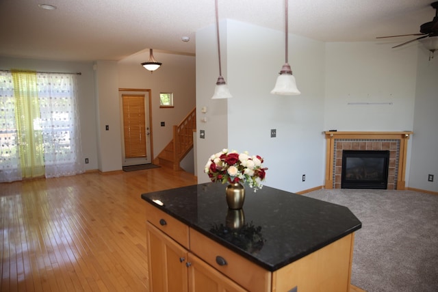 2690 Pinkspire Ln E, Maplewood, MN 55119 - kitchen with open floor plan, ceiling fan, a tiled fireplace, light wood finished floors, and a center island