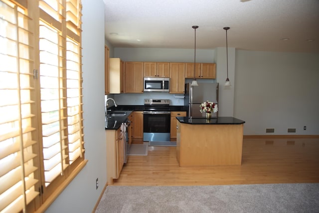 2690 Pinkspire Ln E, Maplewood, MN 55119 - kitchen featuring appliances with stainless steel finishes, a center island, dark countertops, and light colored carpet