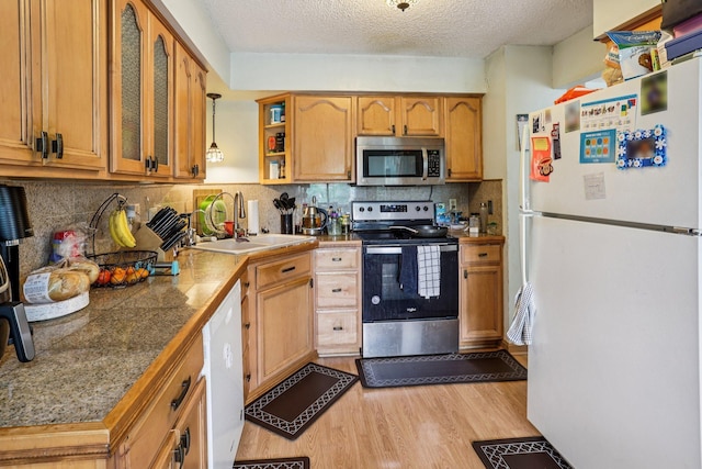 9205 29th Ave N, New Hope, MN 55427 - kitchen with appliances with stainless steel finishes, light wood-style flooring, glass insert cabinets, brown cabinetry, and backsplash