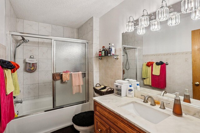 9205 29th Ave N, New Hope, MN 55427 - full bath with tile walls, a textured ceiling, vanity, and combined bath / shower with glass door