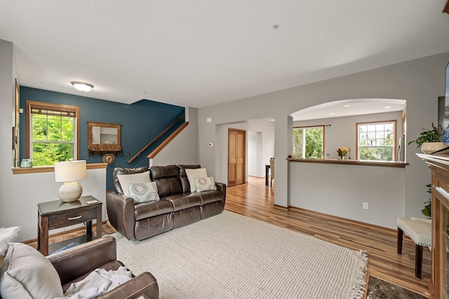 8291 Labont Way, Eden Prairie, MN 55344 - living room featuring wood finished floors, arched walkways, a fireplace, and stairs