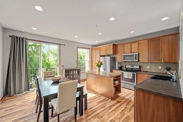 8291 Labont Way, Eden Prairie, MN 55344 - kitchen featuring appliances with stainless steel finishes, dark countertops, a kitchen island, light wood-type flooring, and decorative backsplash