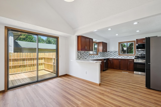 8341 Abbott Ave N, Brooklyn Park, MN 55443 - kitchen featuring stainless steel appliances, light countertops, light wood-style flooring, decorative backsplash, and vaulted ceiling