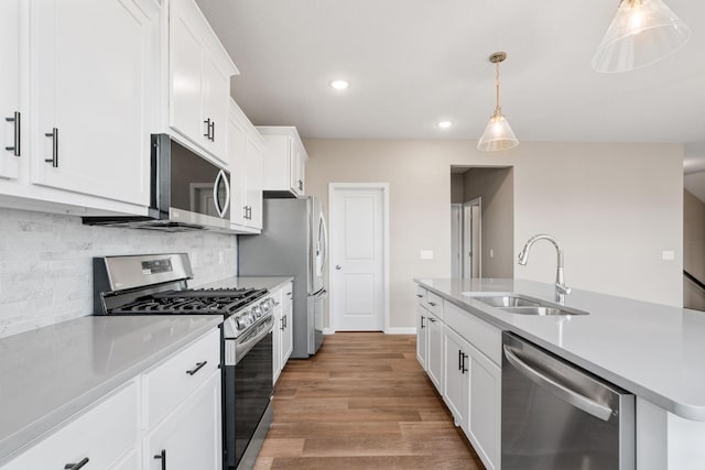 17233 61st St NE, Otsego, MN 55374 - kitchen featuring stainless steel appliances, light countertops, white cabinets, a center island with sink, and light wood-style flooring