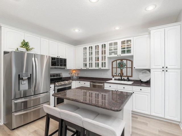 2606 Boulder Way, Burnsville, MN 55337 - kitchen featuring appliances with stainless steel finishes, a breakfast bar, glass insert cabinets, light wood-type flooring, and recessed lighting