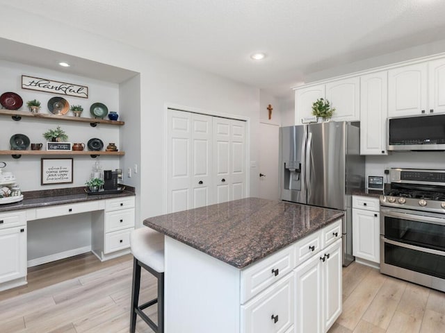 2606 Boulder Way, Burnsville, MN 55337 - kitchen featuring appliances with stainless steel finishes, light wood-type flooring, built in desk, white cabinetry, and dark stone countertops
