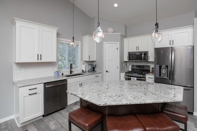 3875 Virgo Ln SW, Rochester, MN 55902 - kitchen featuring appliances with stainless steel finishes, a breakfast bar area, lofted ceiling, white cabinets, and tasteful backsplash