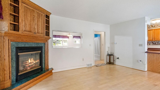 507 15th St SE, Menomonie, WI 54751 - unfurnished living room featuring a glass covered fireplace, light wood-type flooring, and a textured ceiling