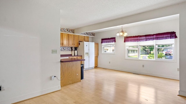 507 15th St SE, Menomonie, WI 54751 - kitchen featuring white refrigerator with ice dispenser, a chandelier, light wood-style flooring, a textured ceiling, and decorative light fixtures