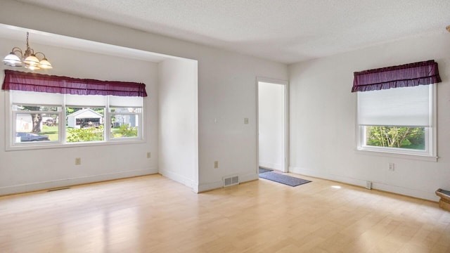 507 15th St SE, Menomonie, WI 54751 - spare room with plenty of natural light, a chandelier, a textured ceiling, and wood finished floors