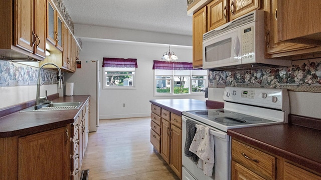 507 15th St SE, Menomonie, WI 54751 - kitchen with white appliances, dark countertops, brown cabinets, light wood-style floors, and glass insert cabinets