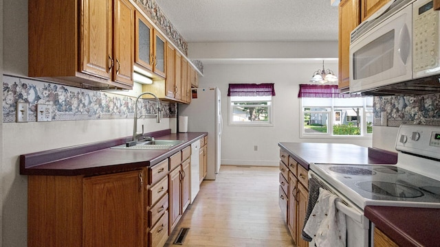 507 15th St SE, Menomonie, WI 54751 - kitchen featuring white appliances, brown cabinetry, dark countertops, light wood-type flooring, and glass insert cabinets