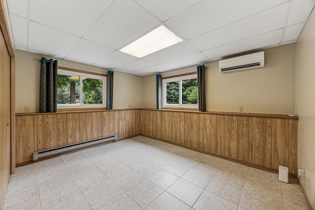 487 Lois Ln, Lino Lakes, MN 55014 - empty room with a baseboard radiator, an AC wall unit, a drop ceiling, plenty of natural light, and wainscoting