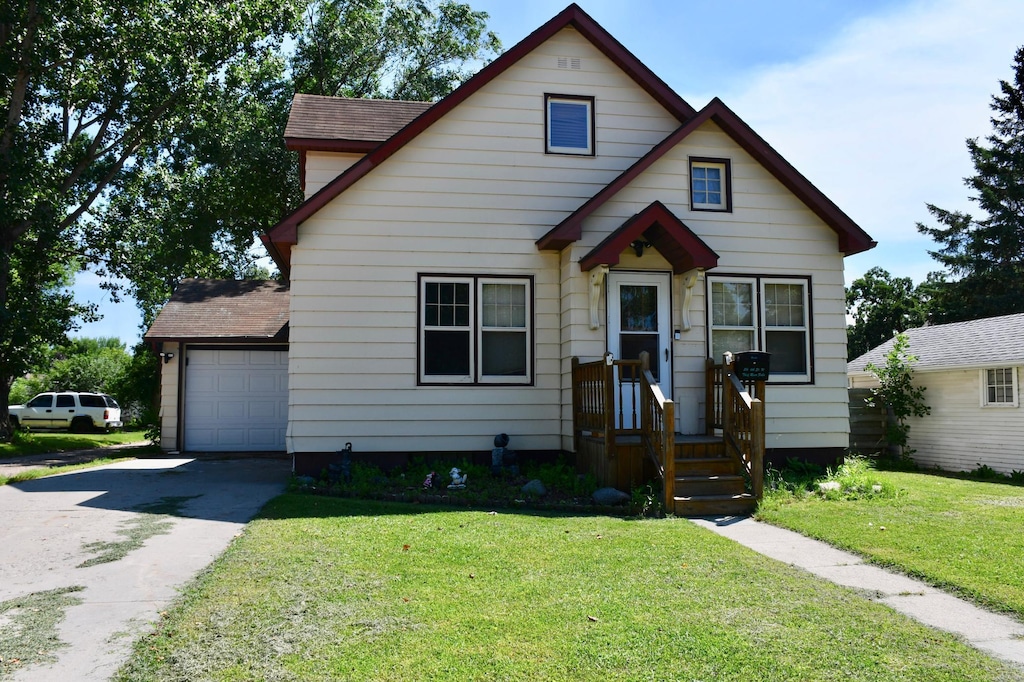 216 6th St W, Thief River Falls, MN 56701 - bungalow-style home featuring driveway, a front yard, roof with shingles, and a garage