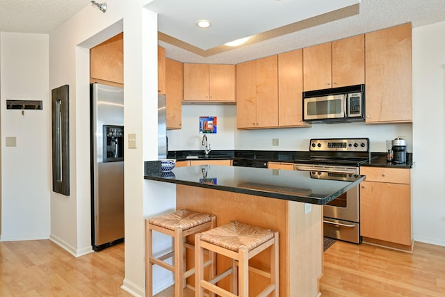 401 1st St Unit 1312, Minneapolis, MN 55401 - kitchen featuring stainless steel appliances, a kitchen breakfast bar, light wood-style floors, light brown cabinetry, and recessed lighting