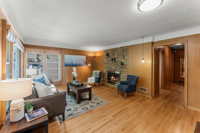 1228 Palace Ave, Saint Paul, MN 55105 - living area with a textured ceiling, a stone fireplace, light wood-type flooring, and wooden walls