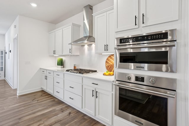 15101 Quince St NW, Andover, MN 55304 - kitchen with wall chimney exhaust hood, appliances with stainless steel finishes, white cabinets, light wood-style floors, and light countertops
