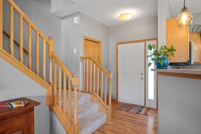 1358 Phalen Blvd, Saint Paul, MN 55106 - entrance foyer with light wood-style floors, a textured ceiling, and stairs