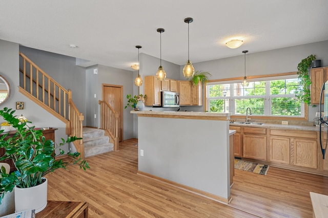 1358 Phalen Blvd, Saint Paul, MN 55106 - kitchen featuring stainless steel microwave, light wood-style floors, light countertops, and hanging light fixtures